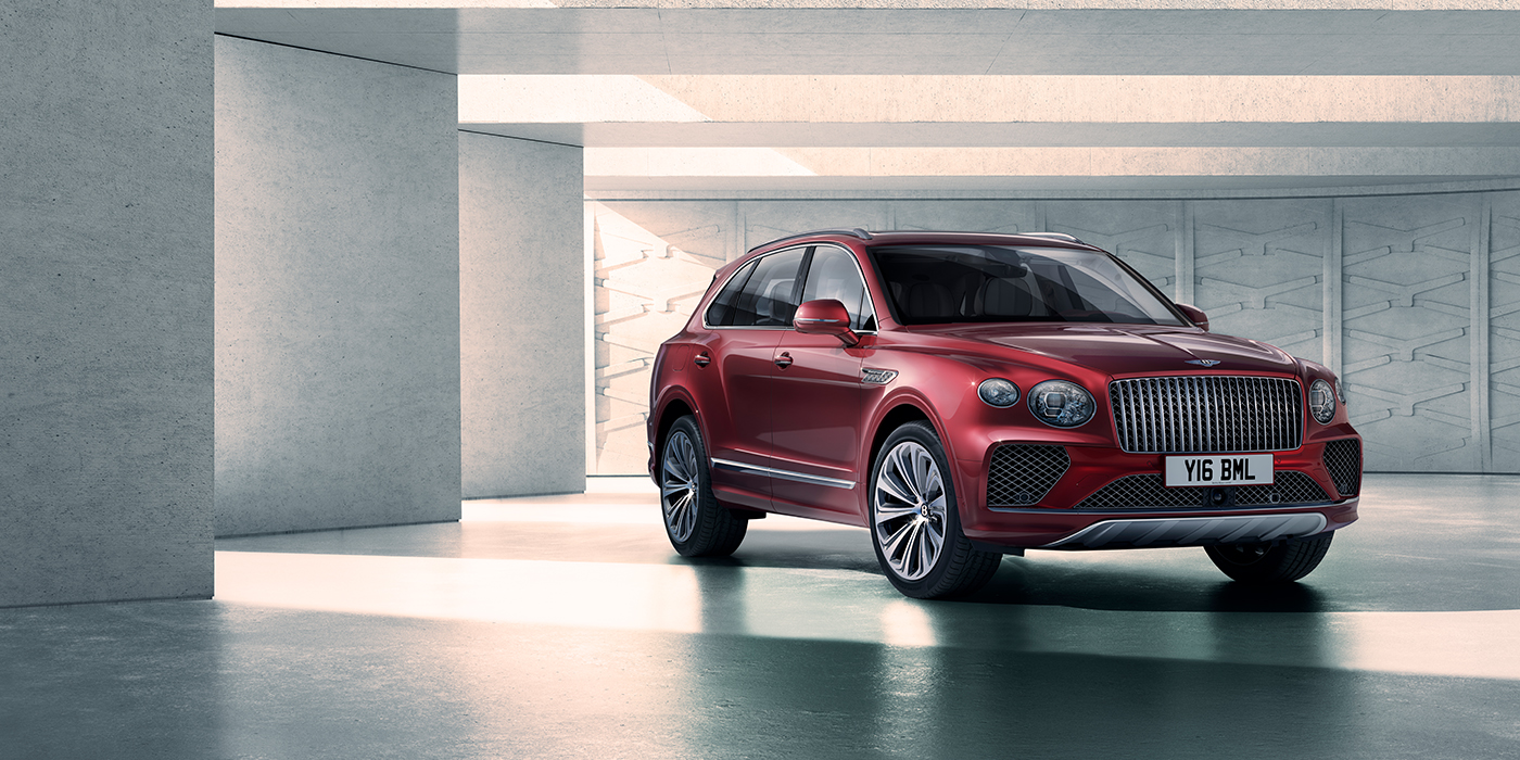 Bentley Dubai Bentley Bentayga Atelier Edition SUV in Rubino Red paint front three quarter against textured concrete wall