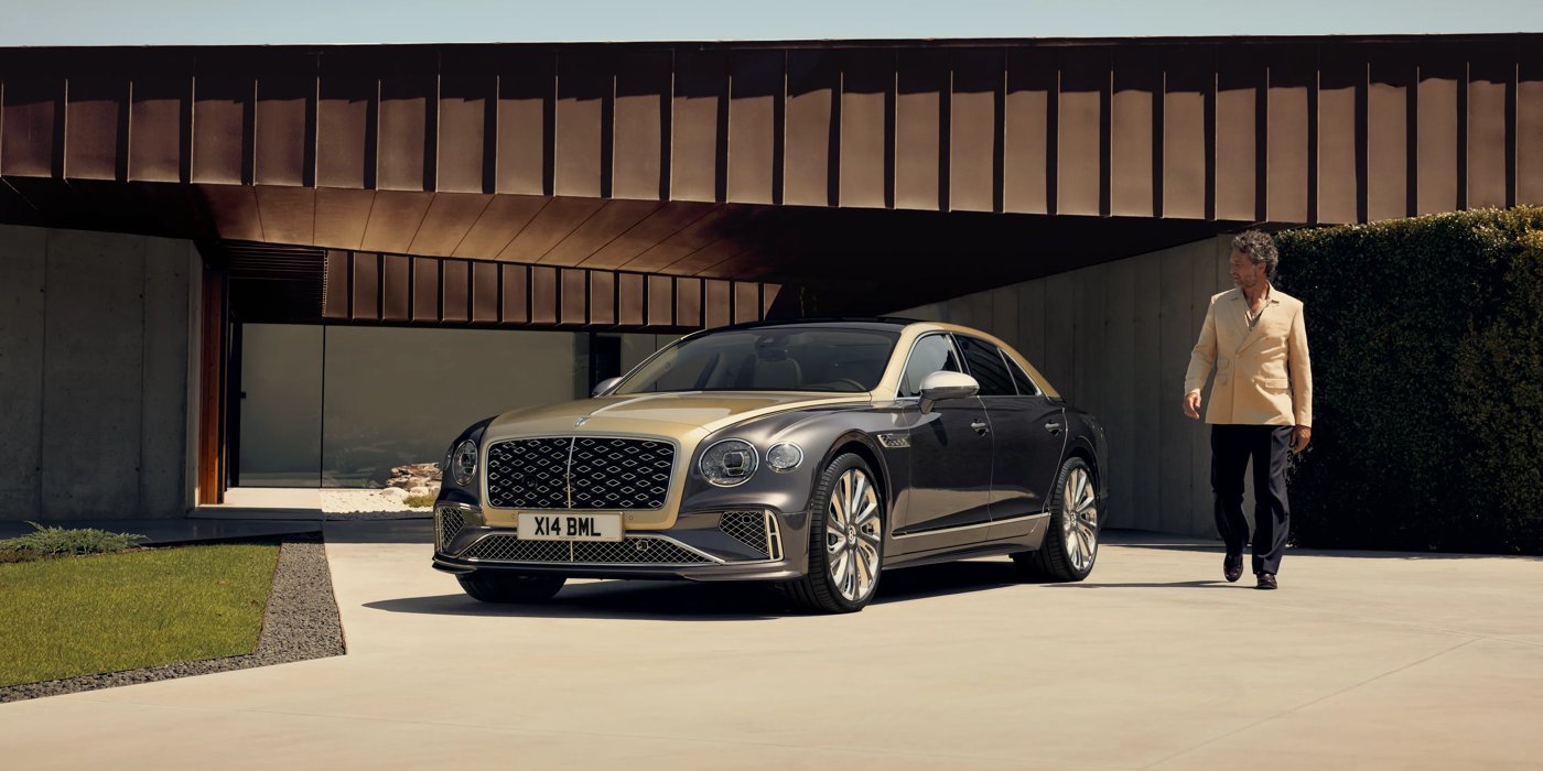 Bentley Dubai Bentley New Flying Spur Mulliner V8 hybrid sedan front three quarters in Rose Gold over Magnetic paint, parked near modern home