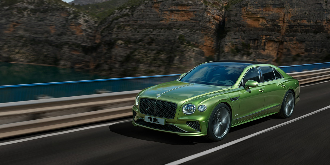 Bentley Dubai Bentley New Flying Spur Speed v8 hybrid sedan driving dynamically on a mountain road in Tourmaline Green paint