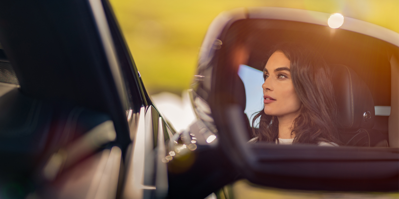 Bentley Dubai profile of dark haired woman's face in mirror of Bentley car in sunlight
