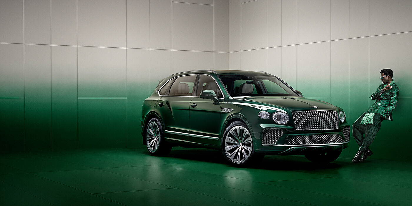 Bentley Dubai Wisdom K leans against wall next to Bentley Bentayga Extended Wheelbase Atelier Edition SUV in Light Emerald green paint