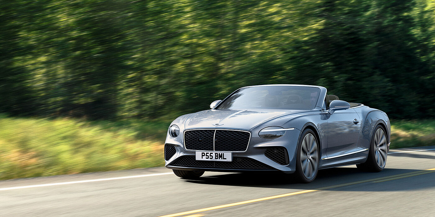 Bentley Dubai New Bentley Continental GTC convertible front view in Silverlake paint with 22 inch ten spoke wheels, driving dynamically on a country road