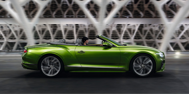 Bentley Dubai Bentley Continental GTC Speed convertible side profile in Tourmaline Green paint driving dynamically on a bridge at night