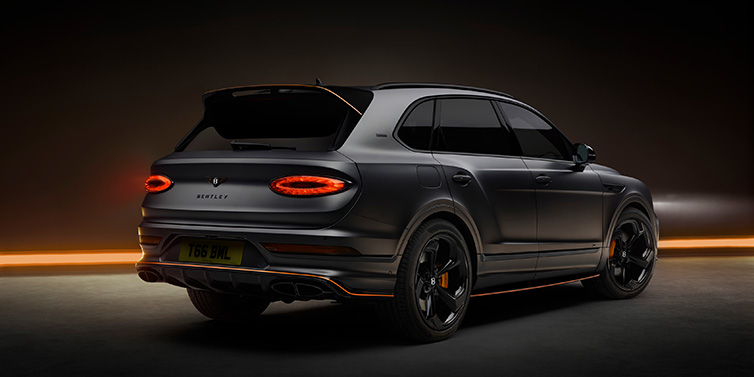 Bentley Dubai Bentley Bentayga S Black Edition SUV rear three quarter in Anthracite Satin paint against a dark red and yellow background