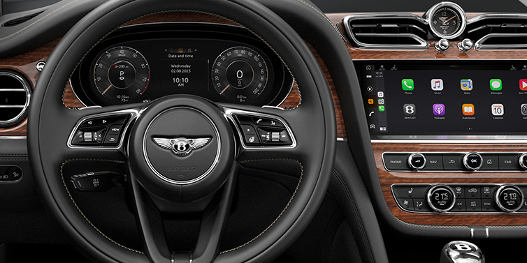 Bentley Dubai Bentley Bentayga SUV front interior detail of steering wheel and driver screens surrounded by Beluga black hide and Crown Cut Walnut veneer